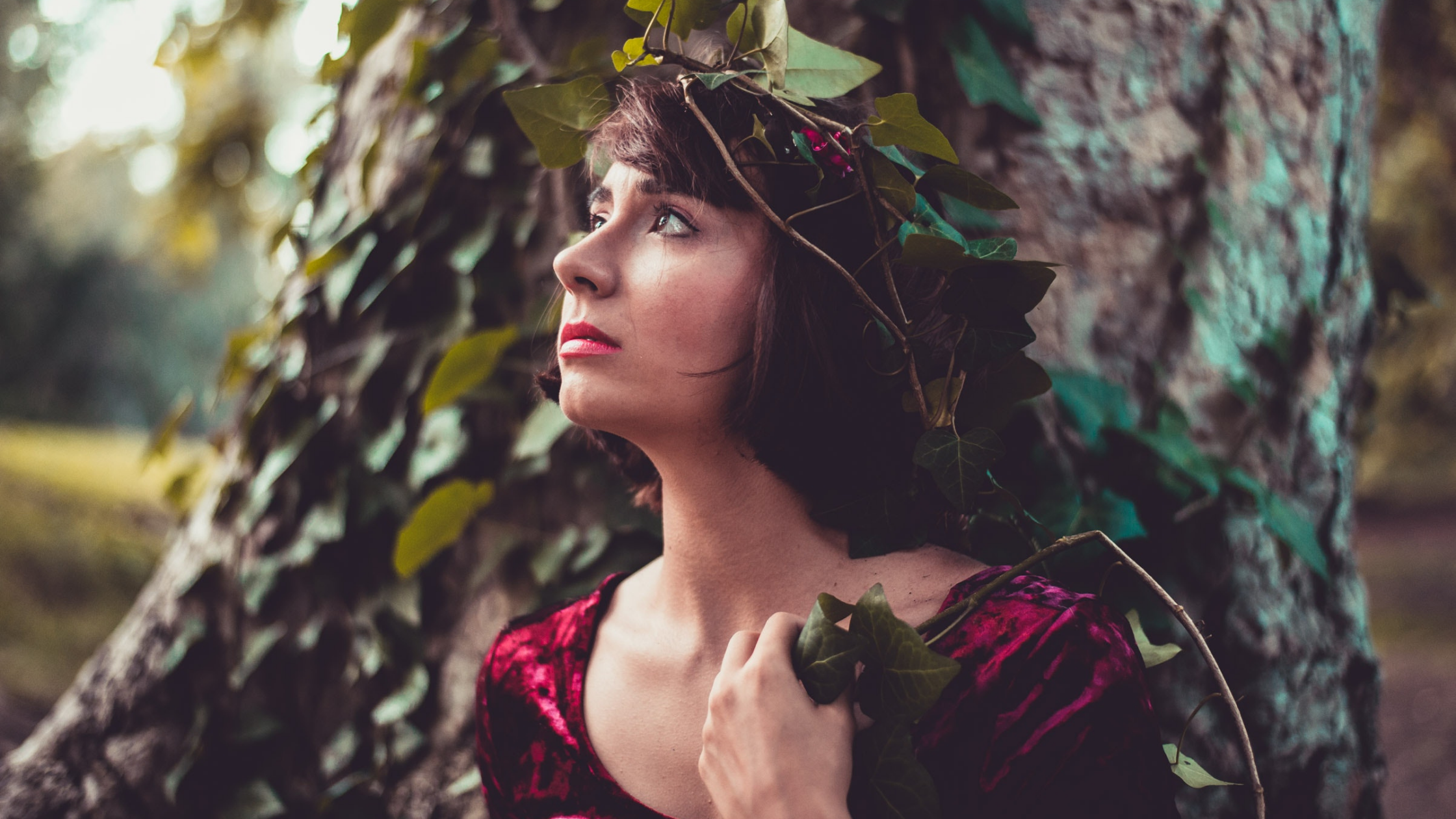 woman in a red dress with an ivy crown staring into the distance